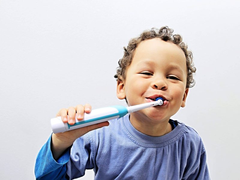 child brushing his teeth with an electric toothbrush