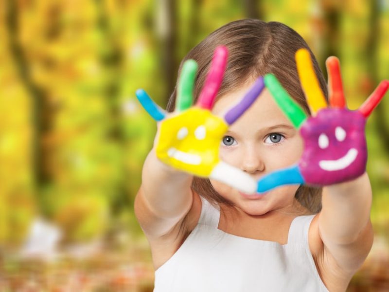 Child holding up painted hands during creative play